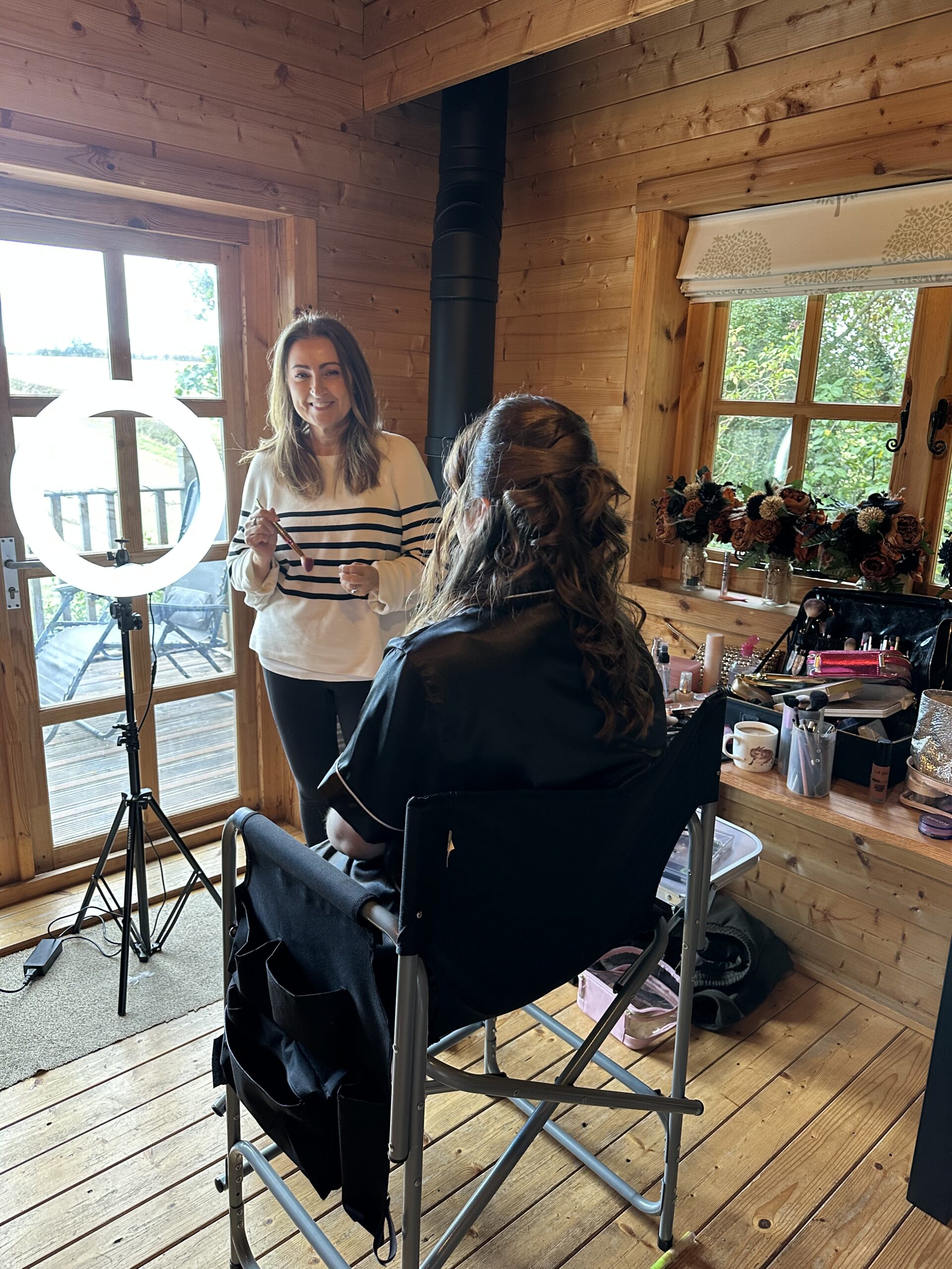 Mel England with a client beside her ring light and makeup kit