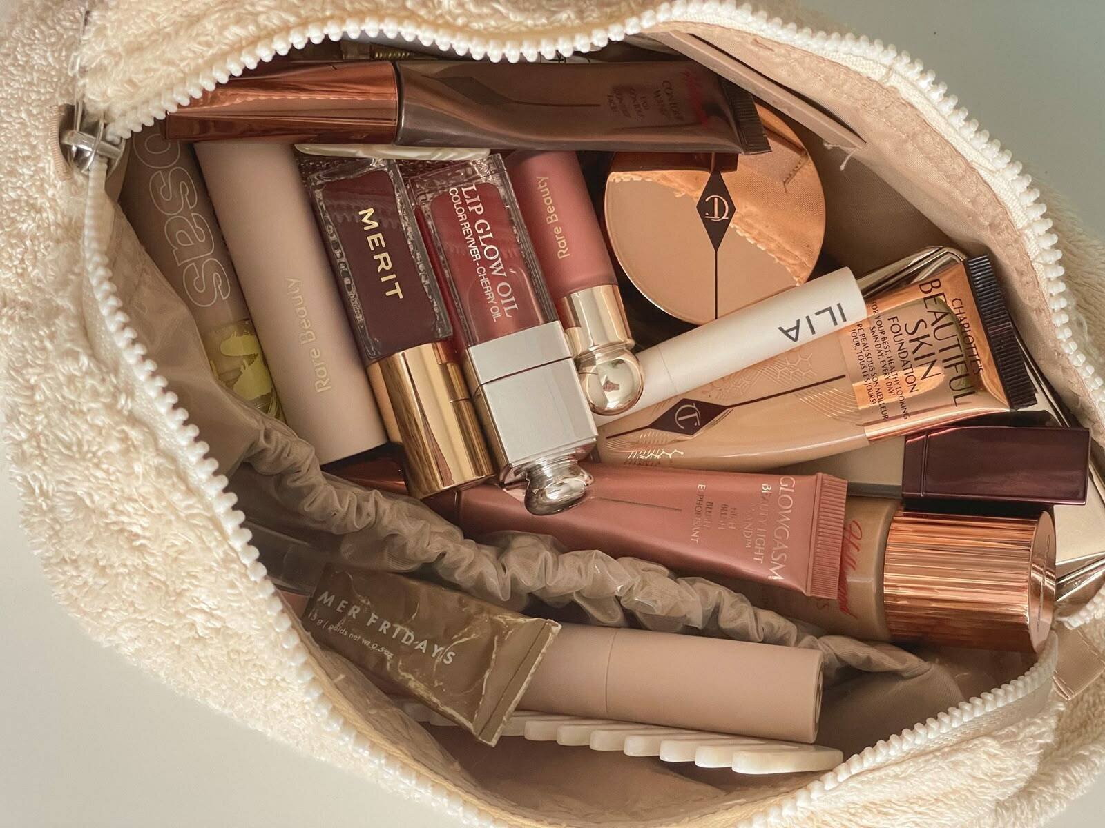 An open cream makeup bag filled with everyday makeup products